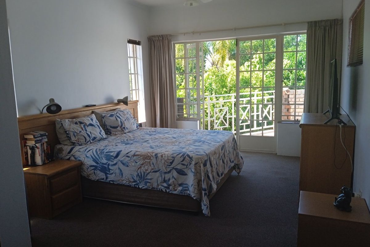 Spacious bedroom featuring carpet flooring, a ceiling fan, and direct access to a private balcony through glass french doors.