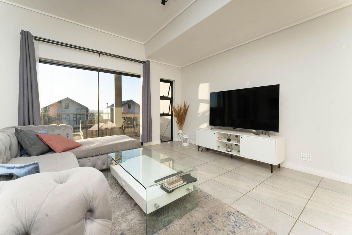 A bright and modern living room featuring large sliding glass doors that provide natural light and access to an outdoor balcony area.