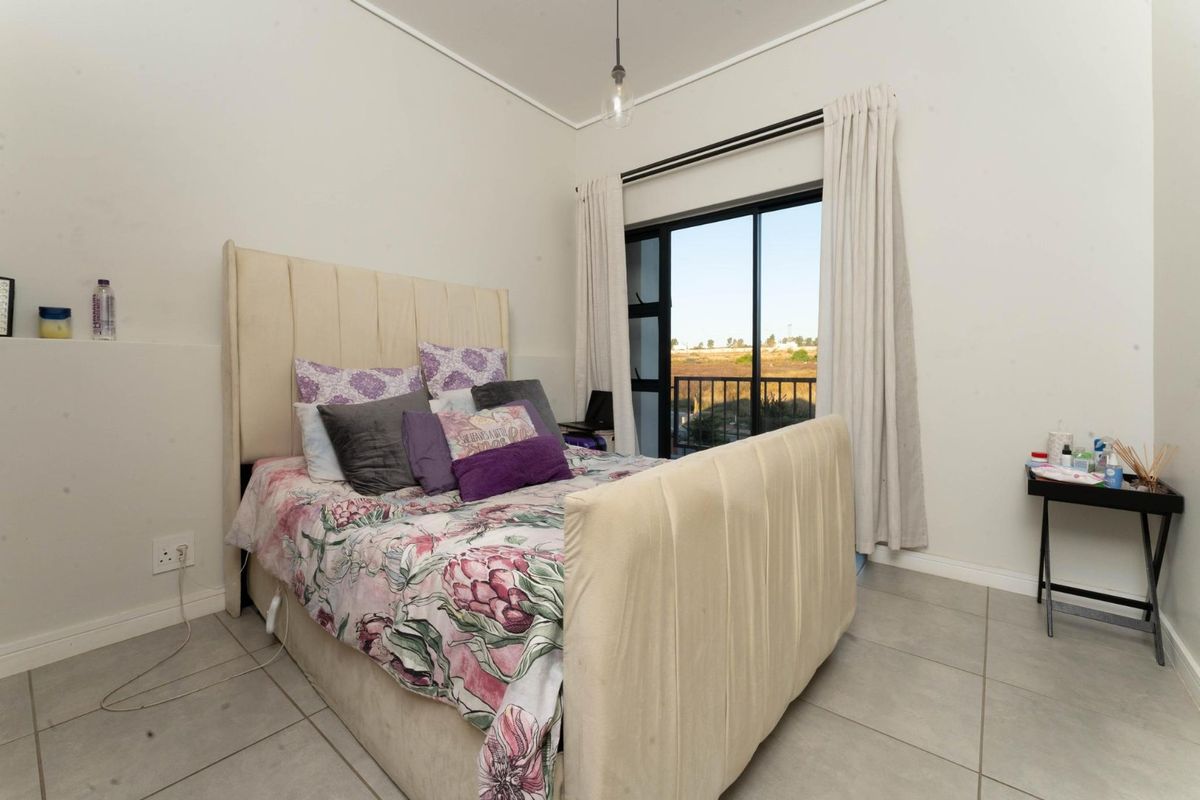 A bedroom featuring tiled flooring, a sliding glass door leading to a balcony, and neutral wall finishes.