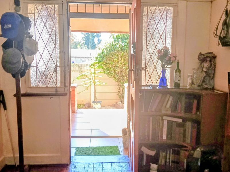 Entrance area featuring a timber door with leaded glass sidelights, opening onto a tiled patio space.