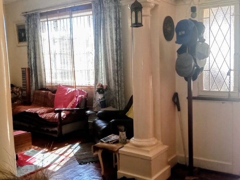 A living room area featuring decorative columns, hardwood flooring, and a leaded glass entrance door, providing a classic architectural aesthetic.