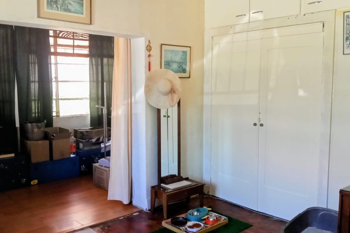 A bedroom featuring built-in cupboards and wooden flooring, showing signs of wear and requiring cosmetic updates to improve its overall condition.