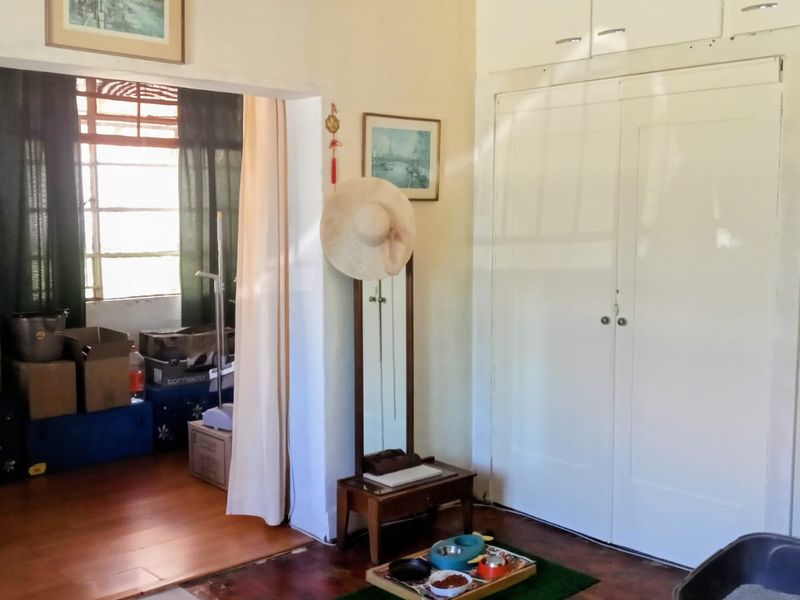 A bedroom featuring built-in cupboards and wooden flooring, showing signs of wear and requiring cosmetic updates to improve its overall condition.