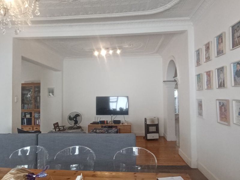 Spacious open-plan living area featuring classic ornate ceilings, hardwood flooring, and an elegant archway connecting the living and dining spaces.
