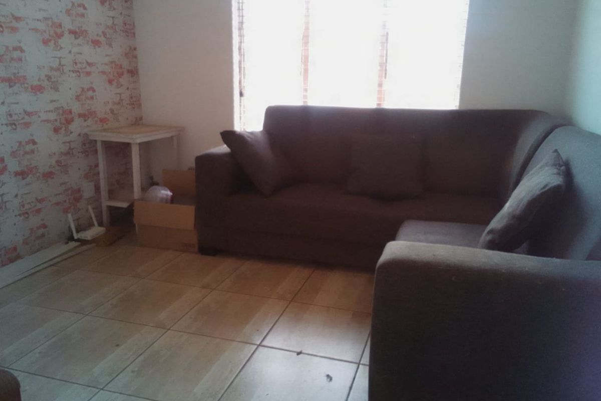 A living room area featuring tiled flooring and window blinds, providing a functional space for relaxation.