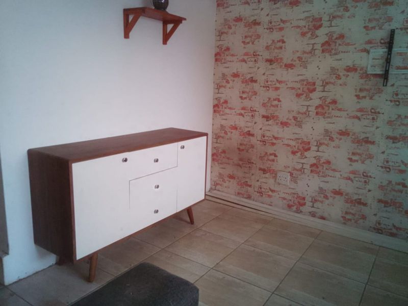 A living area featuring tiled flooring and a decorative brick-effect feature wall.
