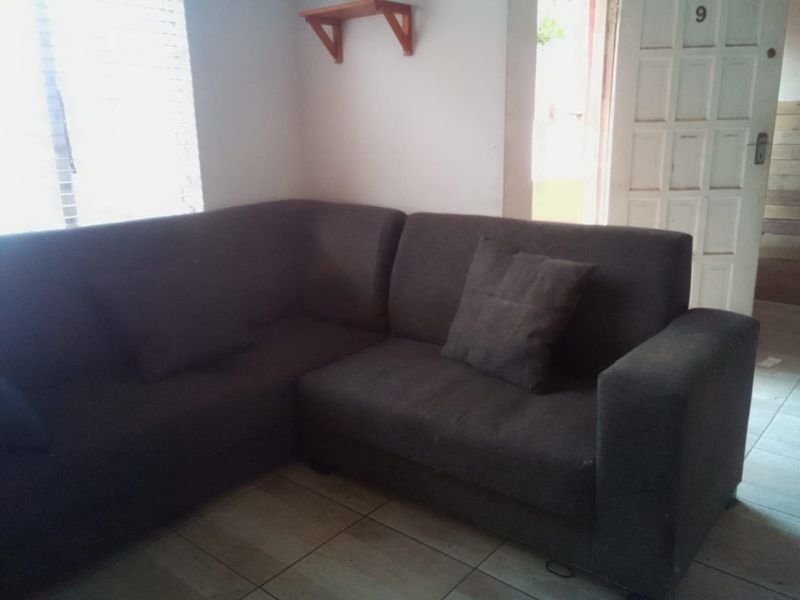 A living room area featuring tiled flooring and a panel door entrance, providing a functional space for relaxation.