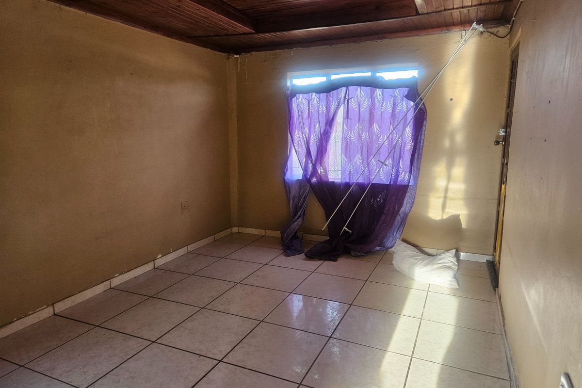 An empty bedroom featuring tiled flooring and a timber ceiling, requiring cosmetic updates to improve its overall appeal and condition.