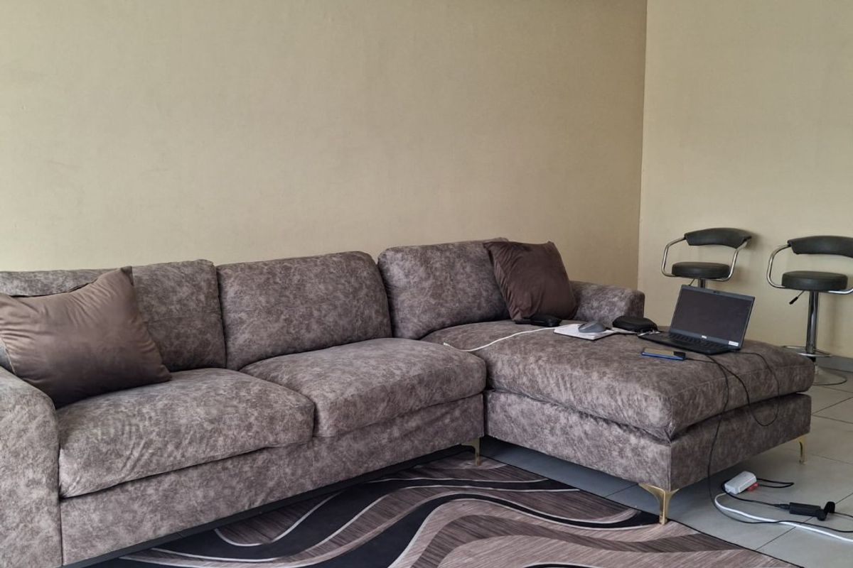 A living room area featuring neutral wall tones, tiled flooring, and a coved ceiling, providing a functional and versatile space for relaxation.