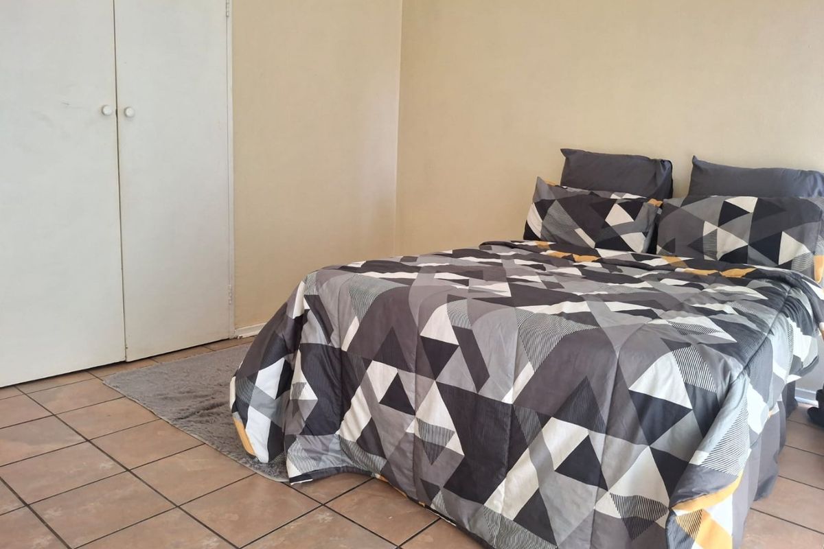 A functional bedroom featuring tiled flooring and a built-in wardrobe, offering a neutral base for personalization.