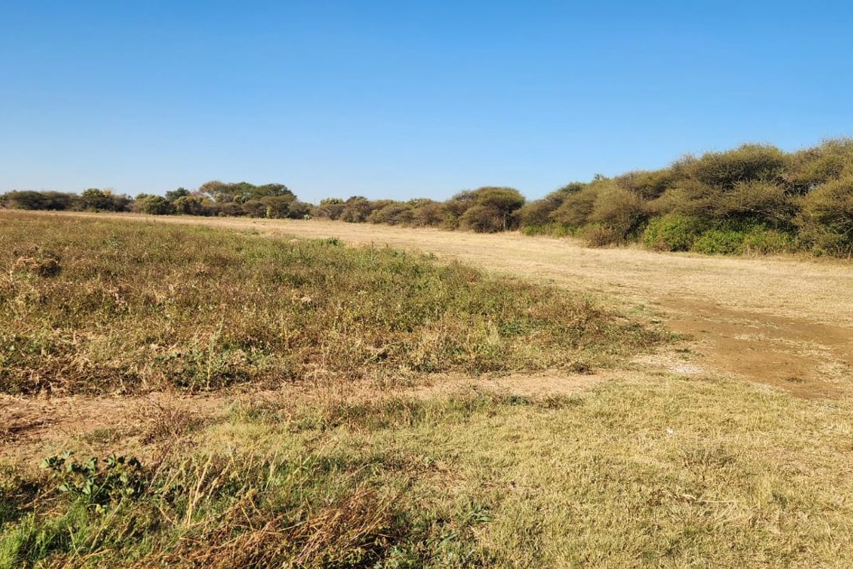 Expansive open farm land featuring natural vegetation and perimeter fencing, suitable for agricultural use or development.