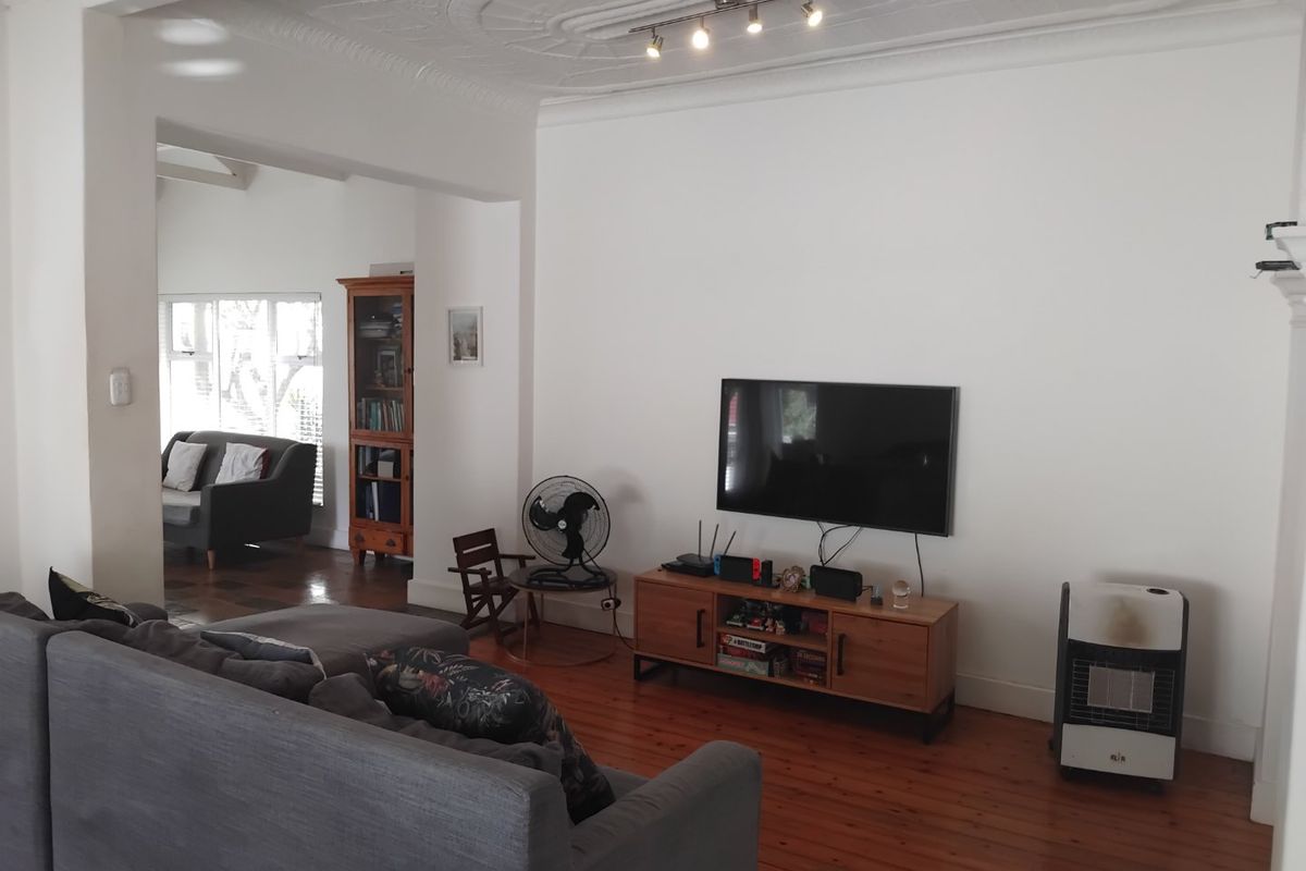 Spacious living room featuring original hardwood flooring, ornate ceiling detailing, and coving, offering a bright and characterful living space.