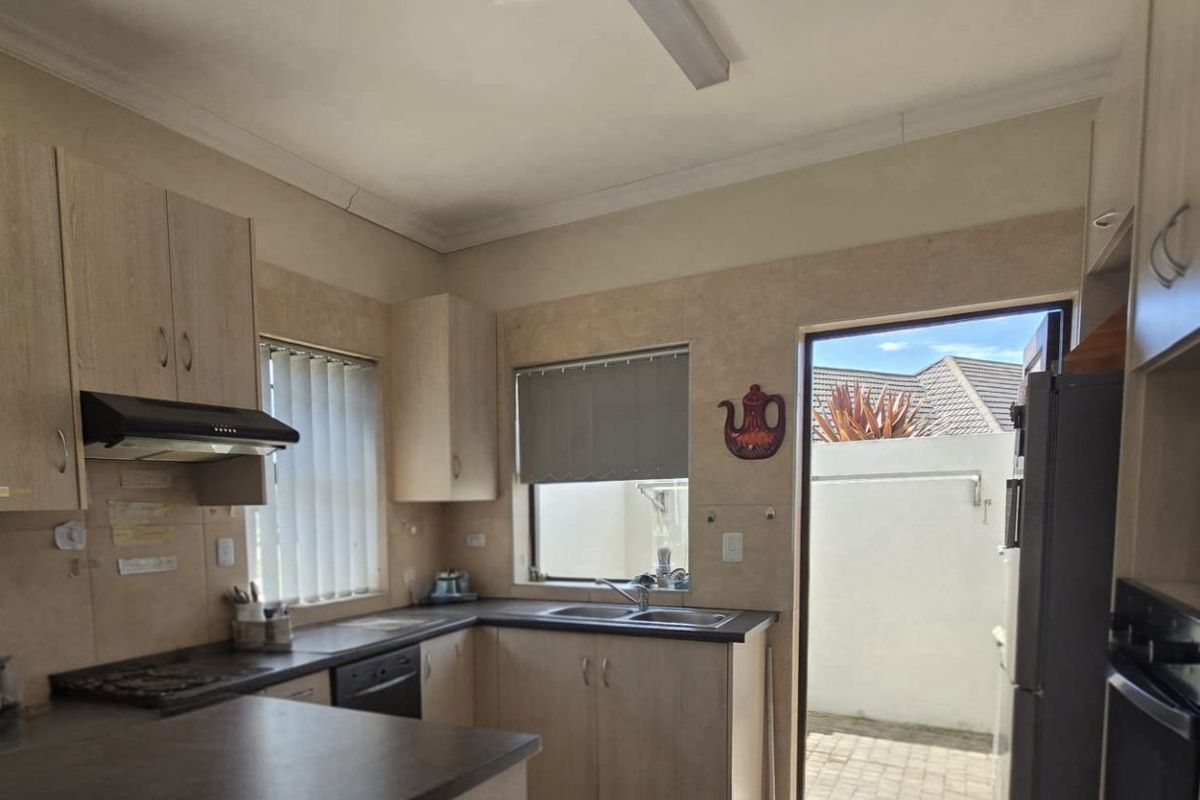 Functional kitchen featuring laminate cabinetry, dark countertops, built-in oven, extractor fan, and direct access to an outdoor paved area.