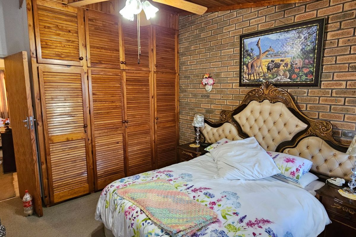 A bedroom featuring an exposed brick feature wall, timber ceiling, and extensive built-in wooden cabinetry for storage.