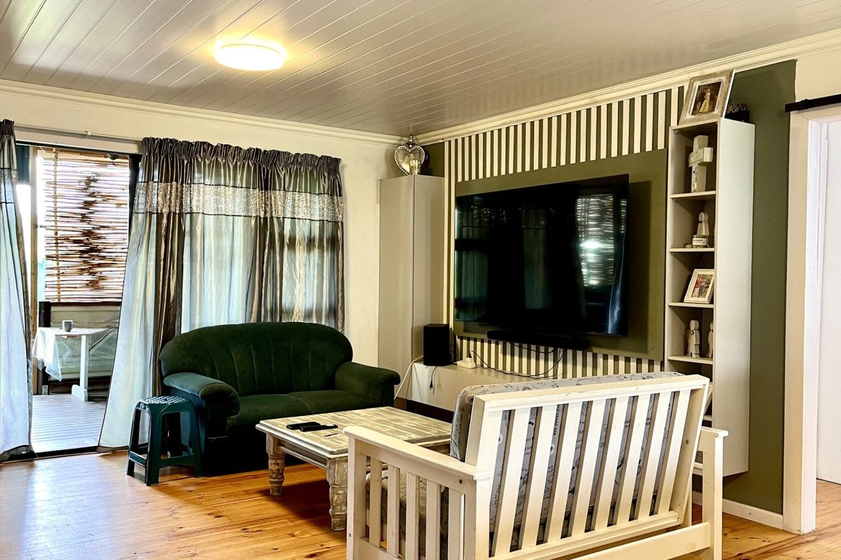 A living room featuring timber flooring, a tongue and groove ceiling, and a sliding glass door providing access to an outdoor patio area.