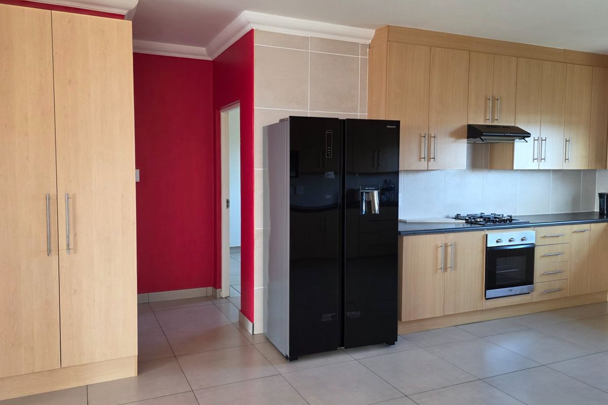 A functional kitchen featuring light wood cabinetry, tiled flooring, and built-in appliances including a gas hob, oven, and extractor fan.