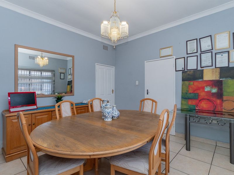 A dining room featuring tiled flooring, cove cornicing, and a central crystal chandelier, providing a functional space for formal meals.