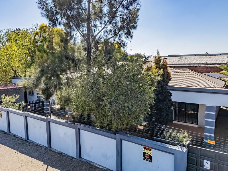 Aerial view of the commercial property frontage featuring a secure perimeter wall with electric fencing, metal gate, and corrugated roof structure.