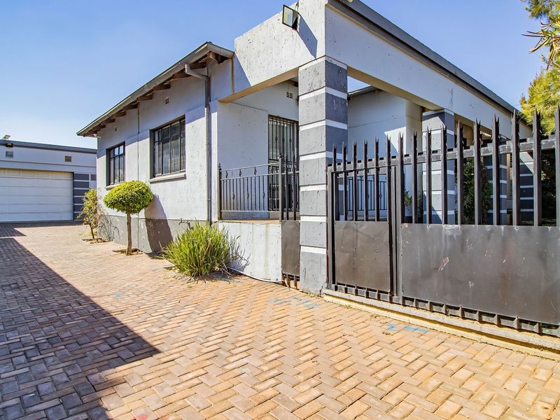 Front exterior view of a commercial property featuring a paved driveway, secure metal gate, and a detached garage structure.