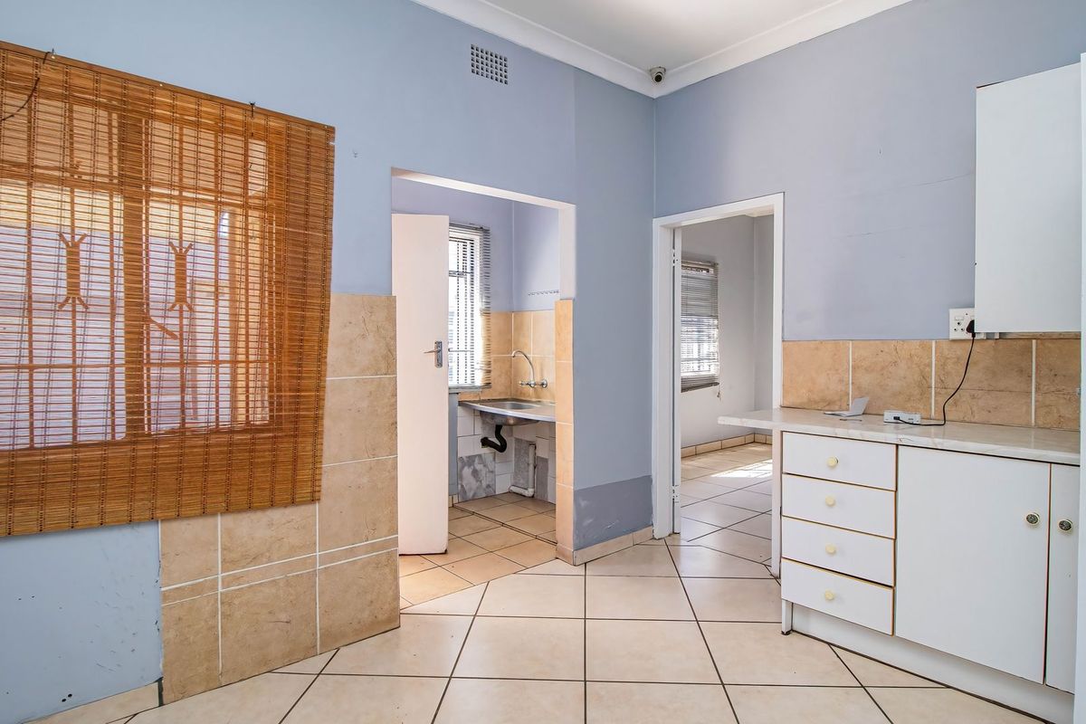 A functional kitchen area featuring tiled flooring, built-in cabinetry, and a tiled splashback, offering a blank canvas for potential renovation and modernization.