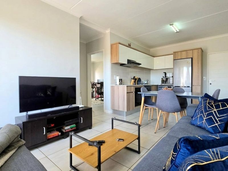 Open-plan living area featuring a modern kitchen with built-in cabinetry, tiled flooring, and a seamless flow into the lounge space.
