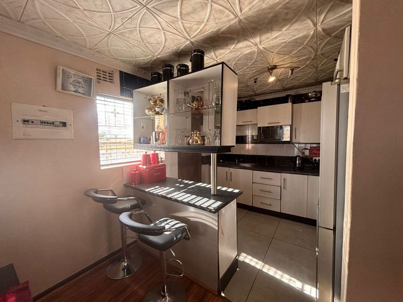 Compact kitchen featuring built-in cabinetry, a breakfast bar, tiled flooring, and decorative ceiling tiles, offering a functional layout with integrated appliance space.