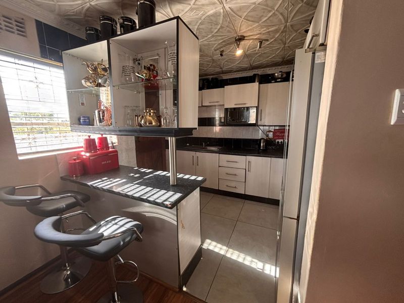 A functional kitchen featuring built-in cabinetry, a breakfast bar, tiled backsplash, and unique decorative ceiling tiles, providing a practical cooking and dining space.
