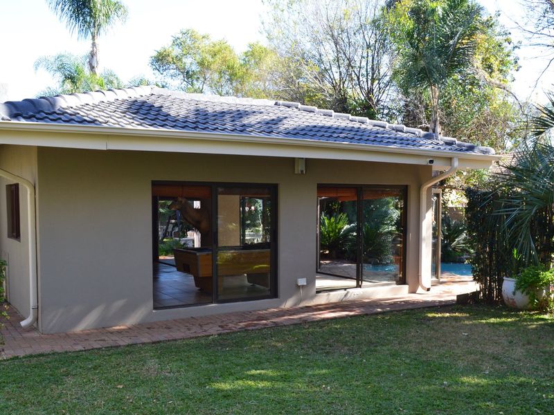 Rear view of the house featuring a tiled roof, brick paved patio area, and large sliding glass doors providing access to the garden.