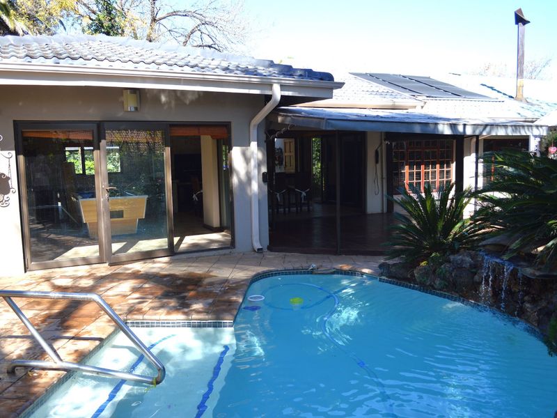 Outdoor pool area featuring a tiled patio, rock waterfall feature, and direct access to the home through sliding glass doors.