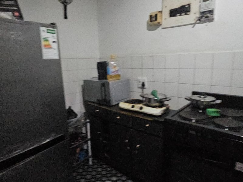 A compact kitchen area featuring dark cabinetry, a tiled splashback, and an electric stove, requiring minor maintenance and cosmetic updates.