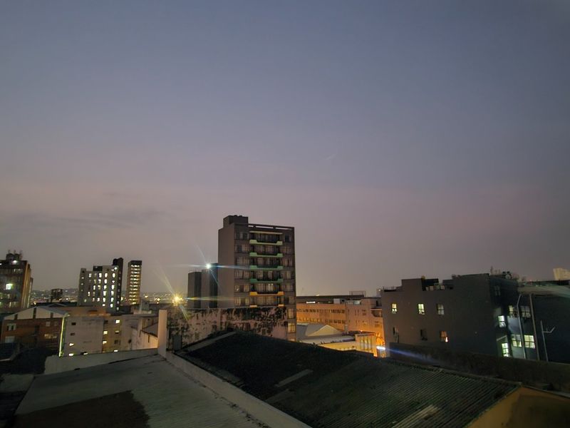 An elevated evening cityscape view overlooking surrounding urban buildings and rooftops.