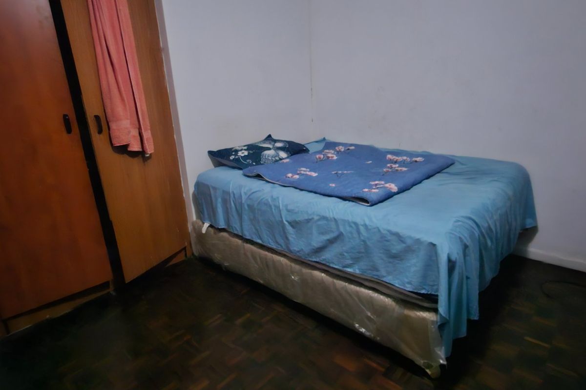 A compact bedroom featuring parquet flooring and a built-in wardrobe, requiring cosmetic updates to the wall finishes and general maintenance.