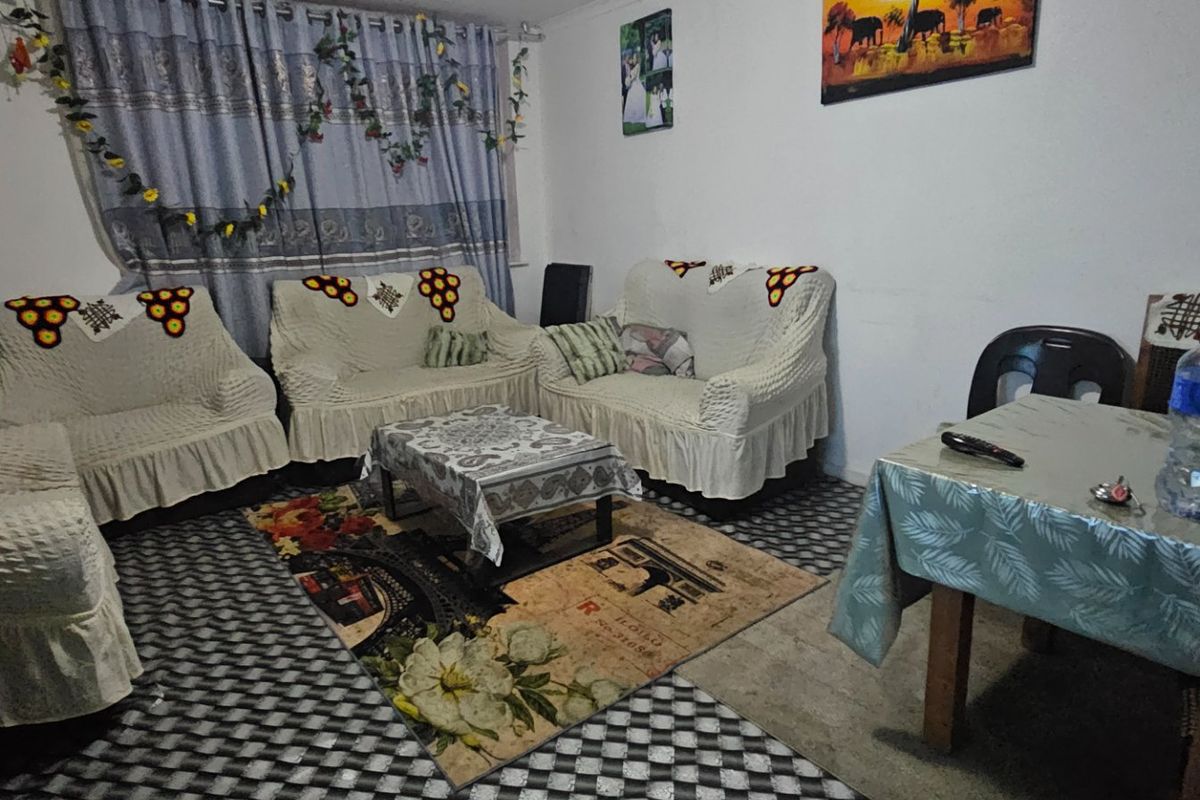 A living room area featuring standard finishes, currently furnished with seating and a dining table.