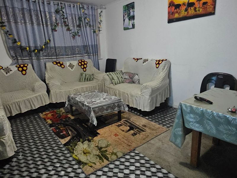 A living room area featuring standard finishes, currently furnished with seating and a dining table.