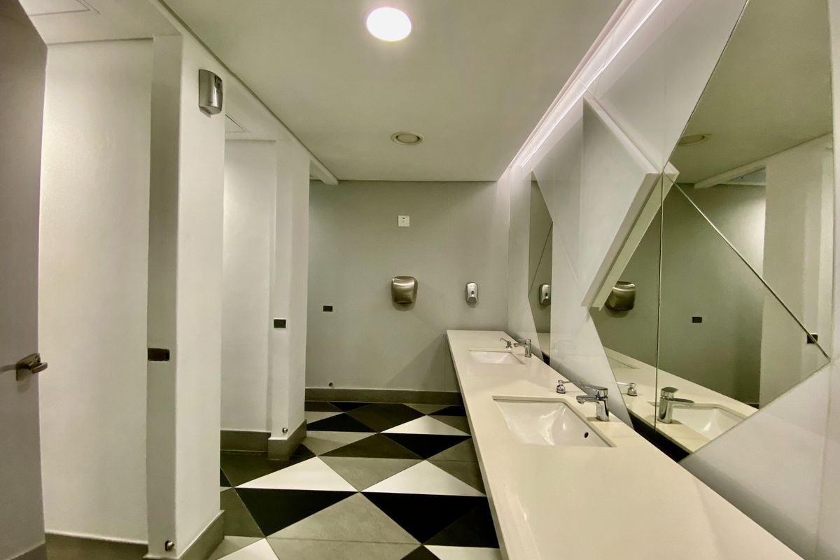 Modern commercial bathroom featuring a sleek double vanity with integrated sinks, geometric floor tiling, and contemporary recessed lighting.