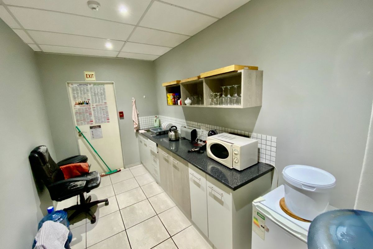 A functional commercial kitchenette featuring laminate cabinetry, granite countertops, tiled backsplash, and a drop ceiling with recessed lighting.