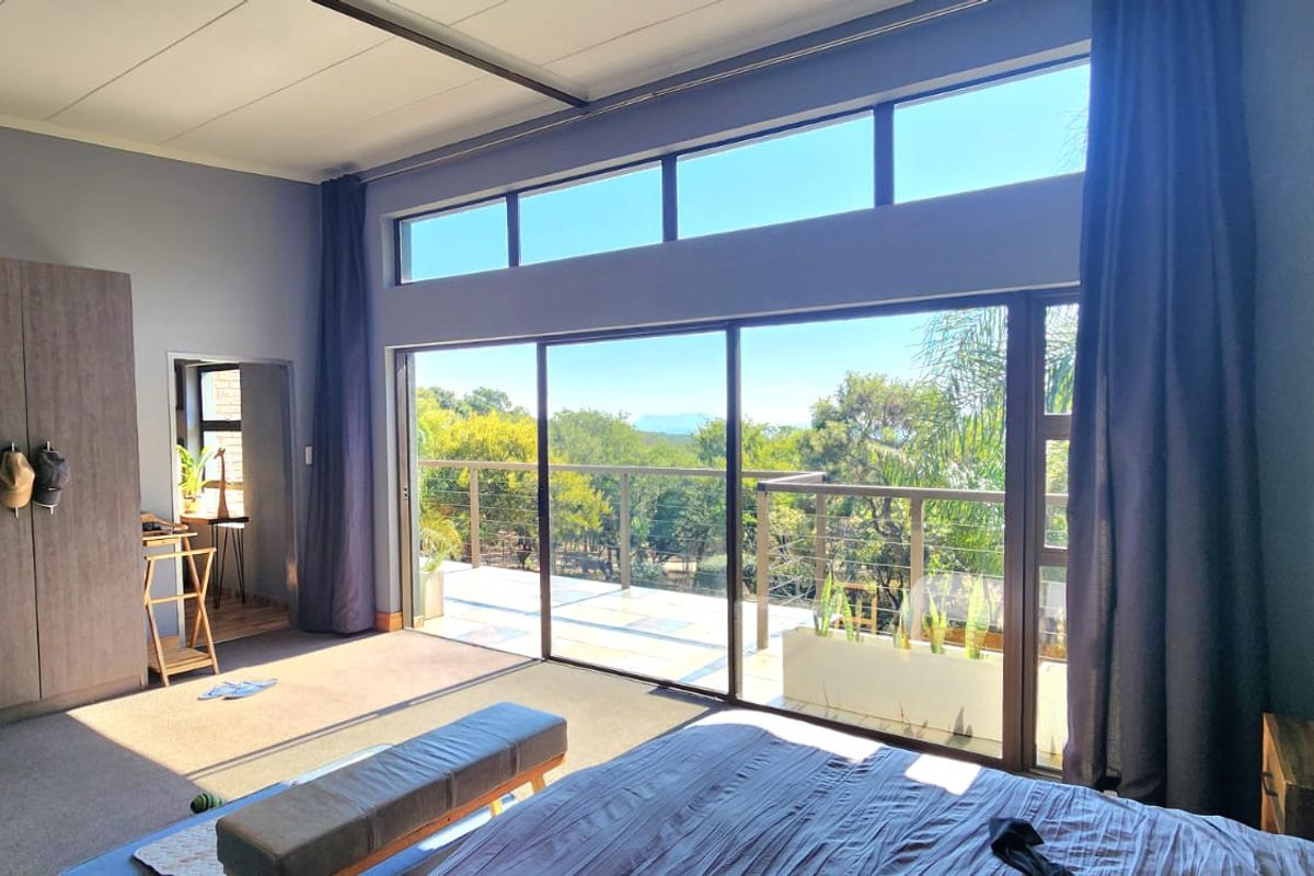 Spacious bedroom featuring large sliding glass doors opening to a balcony, clerestory windows for natural light, and built-in wardrobe storage.