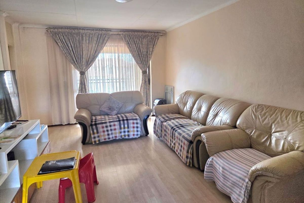 A living room featuring laminate flooring and a sliding glass door providing natural light.