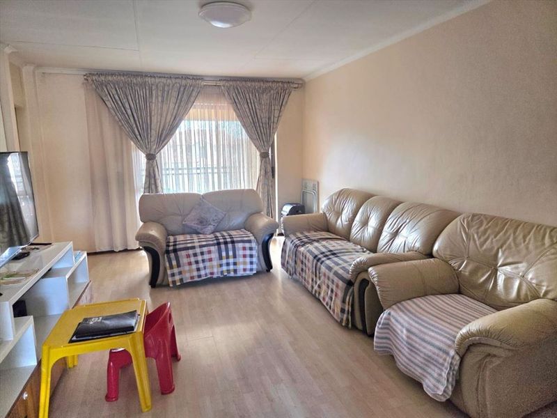 A living room featuring laminate flooring and a sliding glass door providing natural light.