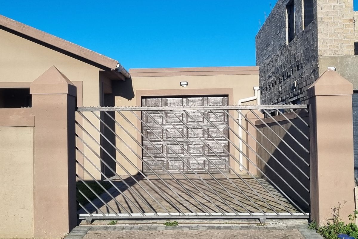 Front view of the property featuring a secure sliding gate, paved driveway, and a single garage door with a neutral exterior finish.