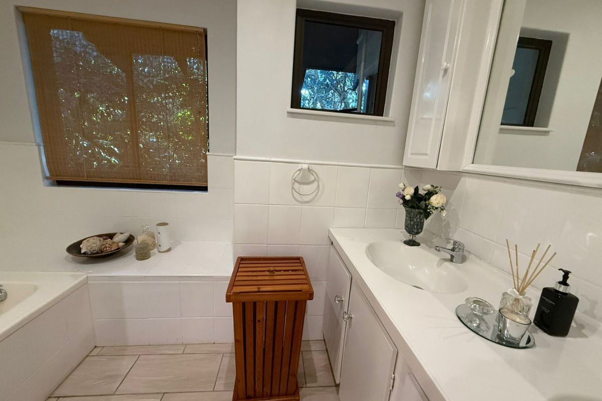 A functional bathroom featuring a built-in vanity with integrated sink, tiled splashback, and a built-in bathtub with tiled surround.