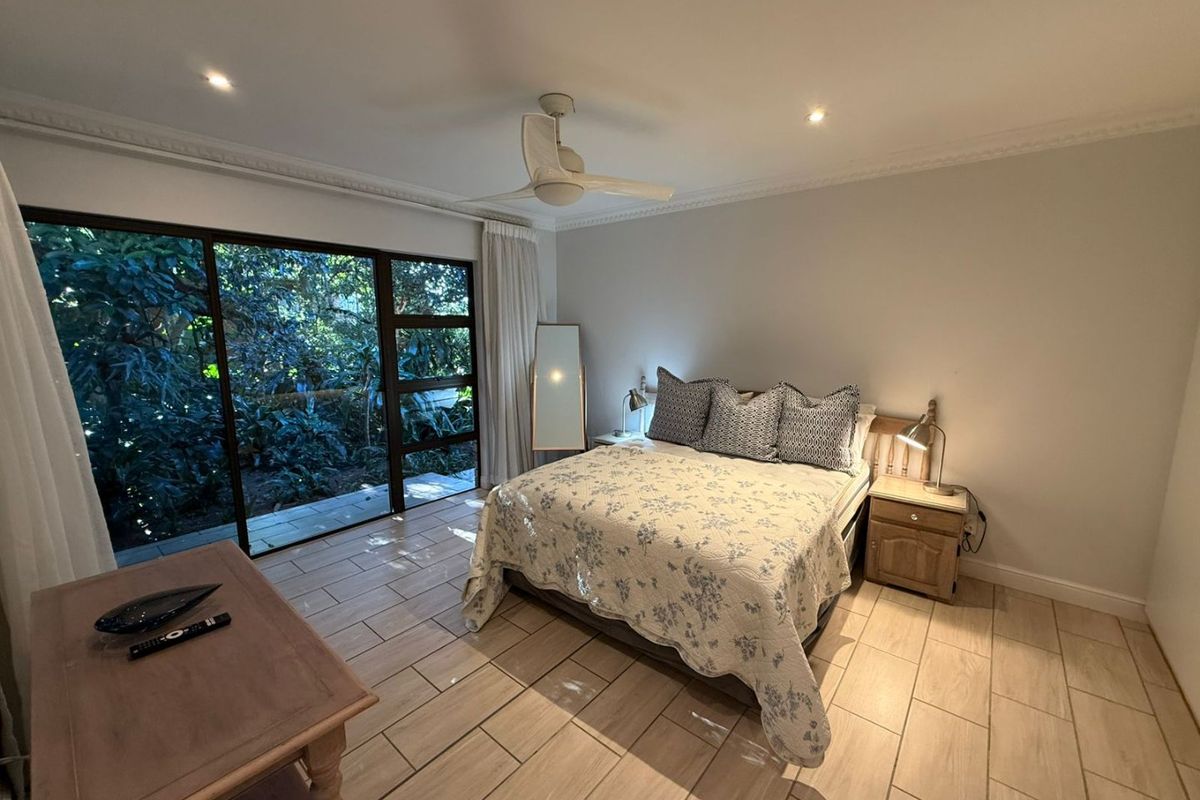 Spacious bedroom featuring tiled flooring, recessed lighting, a ceiling fan, and large sliding glass doors providing direct access to the garden.