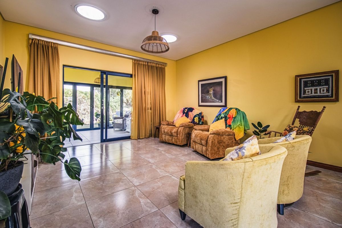 Spacious living room featuring large format floor tiles, natural light from skylights, and sliding glass doors providing seamless access to the outdoor patio area.