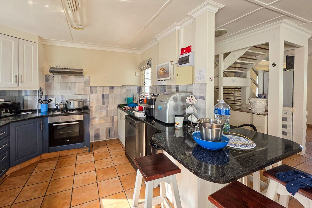 Functional kitchen featuring granite countertops, built-in oven, extractor fan, and tiled flooring, with an adjacent staircase leading to the upper level.