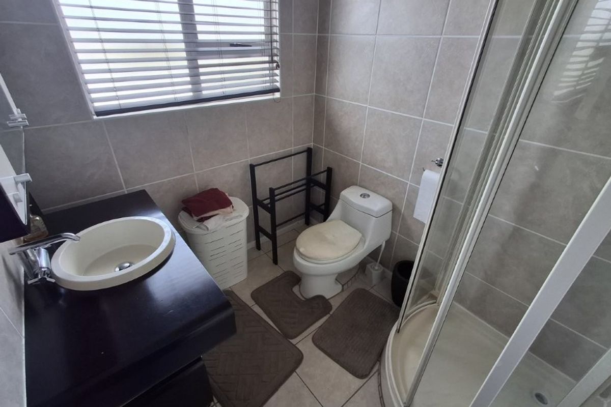 A functional bathroom featuring a corner shower enclosure, vanity basin, and tiled finishes throughout, providing a clean and practical space.