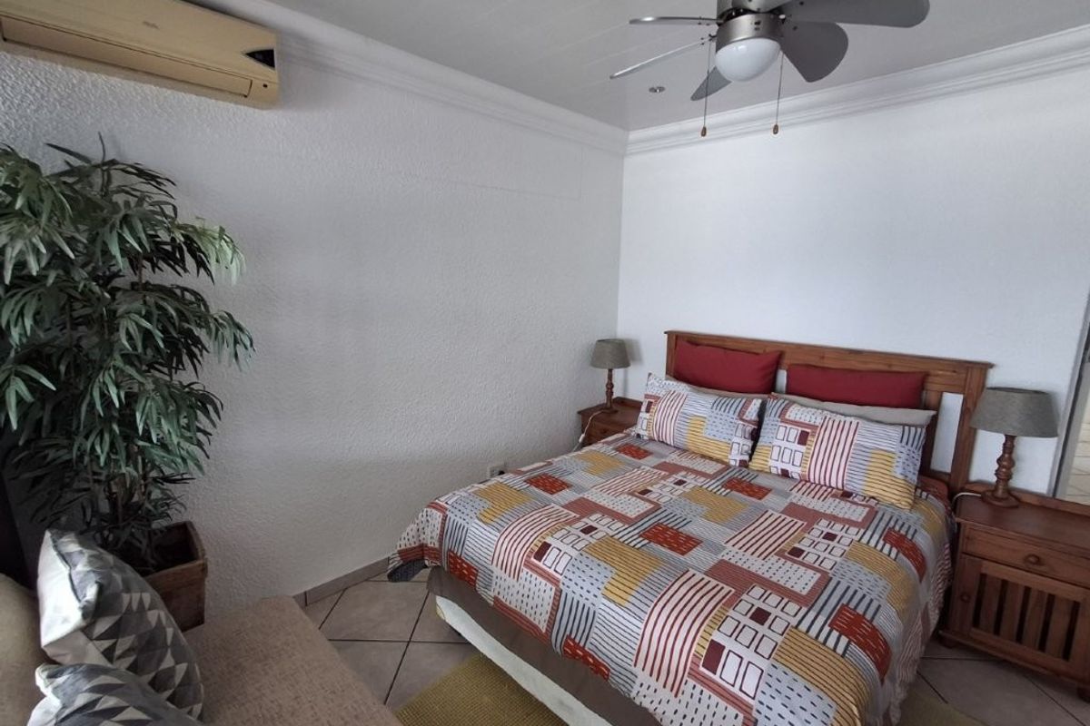 A bedroom featuring tiled flooring, crown molding, a ceiling fan, and a wall-mounted air conditioning unit.