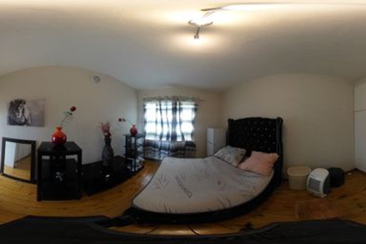 A bedroom featuring timber flooring and extensive built-in cupboard storage, presented in a 360-degree panoramic view.