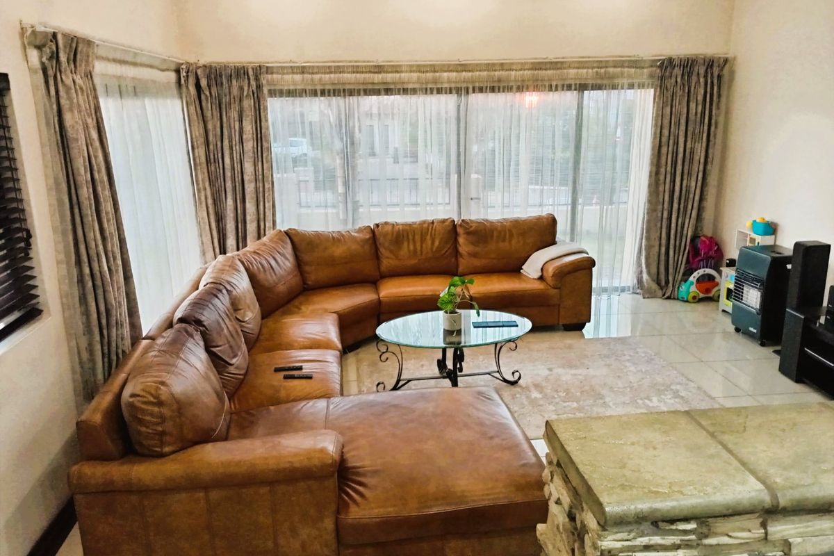 Spacious living room featuring large sliding glass doors that provide ample natural light, tiled flooring, and a stone-clad fireplace hearth.