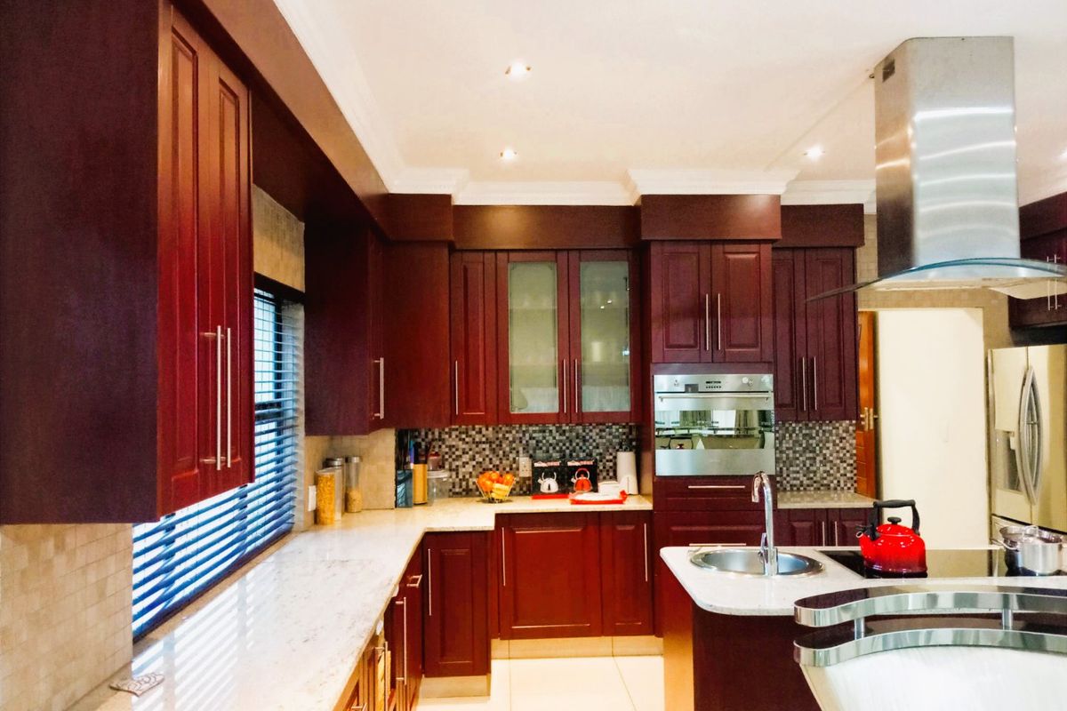 A well-appointed kitchen featuring dark wood cabinetry, stone countertops, a mosaic tile backsplash, and integrated stainless steel appliances.