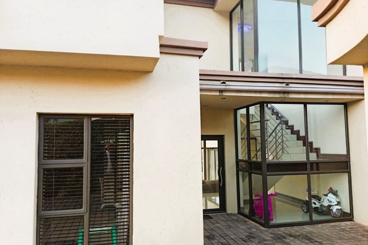 A view of the rear exterior featuring a paved courtyard, large glass windows, and a visible internal staircase.